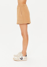 THE UPSIDE women's tan/dune Tecopa Darcy Short features a long-line shape, an elasticated waistband, patch pockets on front and back, and embroidered horseshoe logo on back pocket.