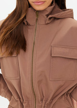 THE UPSIDE women's brown Freddie Fleece Lined Anorak is made with recycled, bonded water resistant fabric. It features a warm polar fleece inner, centre front zipper, external patch pockets, invisible hip pockets, removable hood, concealed drawcord with toggles to cinch in at the waist and a self hanger loop at the inside centre back neck.