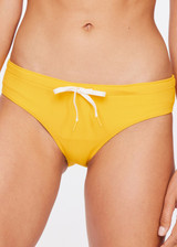 THE UPSIDE women's yellow marigold Dunes Olympia Pant is made from recycled textured rib fabric with moisture wicking properties. The low waisted, classic sporty swim bottom features an elasticated drawcord waist.