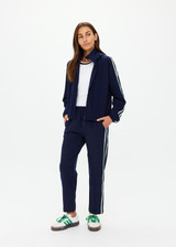 THE UPSIDE women's navy Mansi Dawson Run Jacket is made in a light and breathable recycled fabric, featuring colours of green and white. The run jacket is water resistant and is fitted with elasticated cuffs with inner sleeve gloves and invisible zip pockets and a large back pocket for storing purposes. Designed for golf.