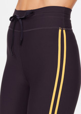 THE UPSIDE women's black Beaufort 25 inch Midi Pant is made from recycled soft peached fabrication with a brushed handfeel for a breathable and quick drying effect. The mid rise pant features an elasticated drawcord for the perfect fit and yellow stripes down the side for style. Designed for the gym and running.