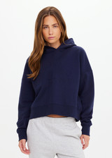 THE UPSIDE women's navy organic cotton Byron Embossed Logo Hoodie is designed for a relaxed boxy fit and features a tonal embossed horseshoe logo on the chest.