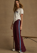 THE UPSIDE women's maroon Ryder Petra Flare Trackpant feature blue side stripes, a split hem, elasticated waist and side pockets.