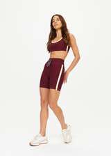 THE UPSIDE women's maroon Trail 6 inch Spin Short is made from soft, breathable fabric and features contrast butter yellow side stripe and an elastic waist.