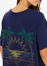 THE UPSIDE women's navy organic cotton Sammi Tee is an oversized fit and features The Upside logo on front and a printed palm tree sunset design on back. Made for lifestyle.