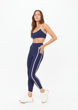 THE UPSIDE women's navy recycled peached Samara 25inch Legging is a soft & supportive fit and features side pockets and contrast cream stripes with curved hem detail. Made for pilates.