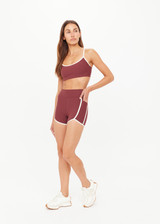 THE UPSIDE women's red recycled peached Samara 3.5inch Spin Short offers a soft & supportive fit and features side pockets and contrast cream stripes. Made for pilates.
