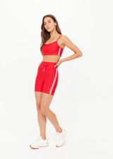 THE UPSIDE women's red eco tech Oxford 5-inch Spin Short is supportive and comfortable with mid-rise, cream side stripes, and elastic waist drawcord. Made for high impact.