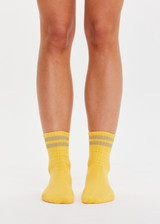 THE UPSIDE women’s yellow Curio Crew Sock with jaquard stripes in gold metallic yarn.