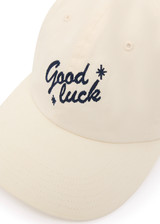 THE UPSIDE women’s cream Good Luck Soft Cap features an embroided 'Good Luck' on front with an adjustable strap at the back.