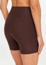 THE UPSIDE women's brown high-waisted Peached 5inch Spin Short offers a soft & supportive fit in recycled peached fabric and features a printed arrow logo on back waistband. Made for pilates & yoga.