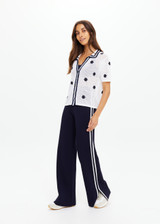 THE UPSIDE women's white organic cotton Piazza Koa Knit Shirt features a ribbed white collar with navy striped placket edge and pearlised shell button closure. Made for everyday.