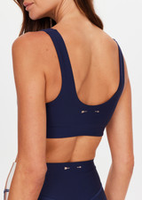 THE UPSIDE women's navy eco tech Toscan Harley Scoop Sports Bra is designed for mid coverage with a scoop front and back neckline, featuring removable cups and crafted with contrast mocha and cream binds. Made for yoga & pilates.