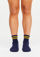 THE UPSIDE women’s navy cotton Salvador Grip Sock is anti slip and has a terry sole with striped yellow midi ankle height. Made for yoga and pilates.