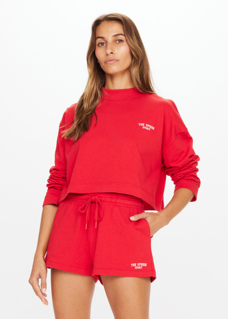 THE UPSIDE Courtsport Sabine Top in Chilli Red is a sustainable organic cotton cropped long sleeve top with ribbed mock neck, printed THE UPSIDE SPORT college logo in white and drop shoulders.