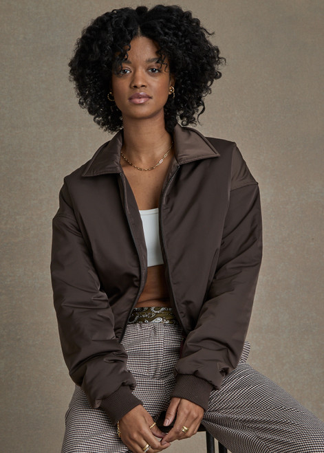 THE UPSIDE women's chocolate-brown cropped Carlotta Jacket made with recycled polyester features a collar, ribbed cuffs, side seam pockets, embossed apple leather patch on back and elastic hemband.