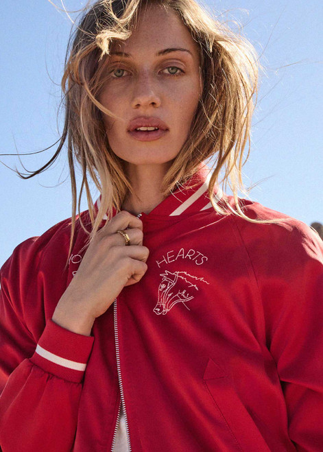 THE UPSIDE women's red 100% silk Two Hearts Silk Bomber Jacket is fully lined with cream and red stripes, welt pockets with triangle detail at top and bottom and an embroidered horse and horseshoe design. Made for lifestyle.