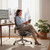 Person sitting comfortably in a Healthy Posture Hinomi X2 Pro ergonomic office chair at a home office desk, demonstrating posture support and modern design.