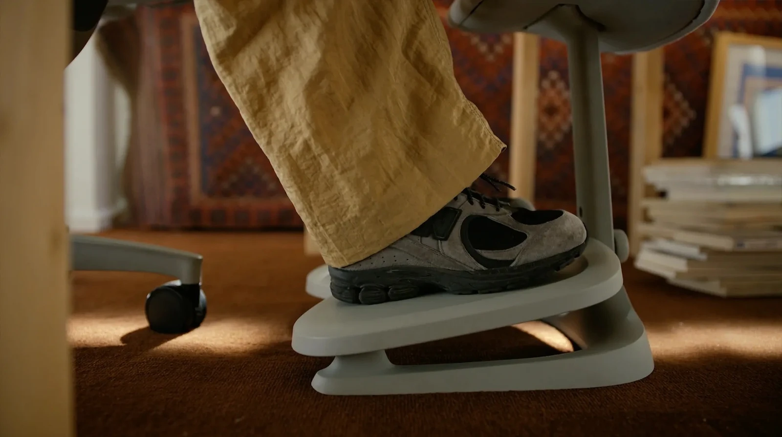 Feet supported on the LiberNovo Maxis StepSync footrest lower platform during seated desk work