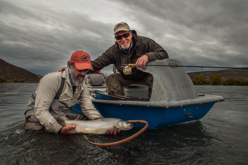 Angler catching a large brown trout while fly fishing in Argentina