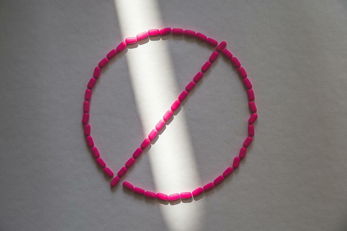 Pink pills outline a crossed-out symbol