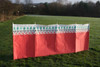 The OLPRO Witley 5 Pole Wooden Windbreak pictured in a campsite in front of a treeline.