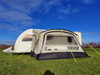 An image of the View Lite 390 Caravan Awning from OLPRO attached to a caravan in a field.