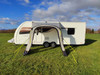 The OLPRO View Lite Breeze 260 Caravan Awning pictured attached to a caravan in a field with all of its doors open from the front.