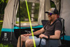 A man sits outside the Snug Poled Tailgate Awning, in an OLPRO camping chair