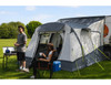 A couple shares a drink outside of the Loopo Breeze® XL v2 Motorhome Awning, they are using OLPRO camping furniture