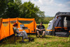 A couple sat outside of a campervan awning and the inflatable windbreak from OLPRO.