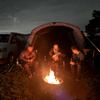 A family sits outside the Cocoon Breeze® v2 Campervan Awning wrapped in blankos surrounding a fire. 