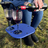 Close-up image of OLPRO Camping Spike Stick Table outside a tent with a glass of wine on top, showing the non-slip matting.