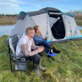Image of OLPRO Camping Spike Stick Table being used by a couple outside a tent by a lake, with a glass of wine on top.