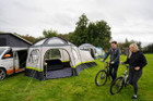 An adult couple walking with bicycles outside of the Hive Campervan Awning Fibreglass Poles - with Sleeping Pod from OLPRO.
