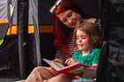 a mother & daughter read inside the Discovery Inflatable Tents darkened sleeping pod