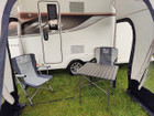 An image of the View Lite 260 Caravan Awning from OLPRO in a field attached to a caravan with some camping furniture inside.