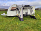 An image of the View Lite 260 Caravan Awning from OLPRO in a field attached to a caravan with some camping furniture inside.