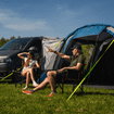 An image of a male and female pointing whilst sat outside of the Cocoon Breeze® v2 Campervan Awning from OLPRO on a volkswagen van, imageset:Blue