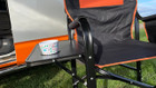 The OLPRO Directors Camping Chair in orange and black with the side table up pictured in front of a VW campervan.