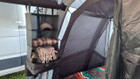 The Camping Organiser with Shelves and Storage Bag by OLPRO hanging in a campervan awning blankets and clothing.