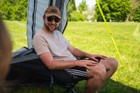 A man sat inside the OLPRO Pershore Breeze® Campervan Canopy. He is sitting on an OLPRO camping chair.