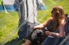 a woman sat inside the OLPRO Pershore Breeze® Campervan Canopy. He is sitting on an OLPRO camping chair
