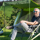 A male sat outside of the Abberley XL 4 Berth Tent by OLPRO at a campsite.