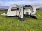 An image of the View Lite 260 Caravan Awning from OLPRO in a field attached to a caravan with some camping furniture inside.