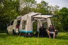 A man sits outside the Snug Poled Tailgate Awning, in an OLPRO directors chair