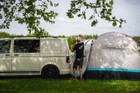 A man sets up the Snug Poled Tailgate Awning on a Volkswagen T5