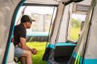 A man sat on the tailgate of A volkswagen T5 inside his snug poled's tunnel