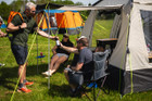 A group of people relaxing outside of the Cubo XL Motorhome Awning - Fibreglass Poles that is attached to a Crafter.