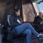 An image of two adults sat on the Henwick Padded Folding Camp Chairs - Grey & Charcoal from OLPRO inside of a tent.